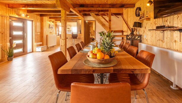 Comedor de madera con una larga mesa dispuesta para seis comensales, rodeada de sillas de cuero.