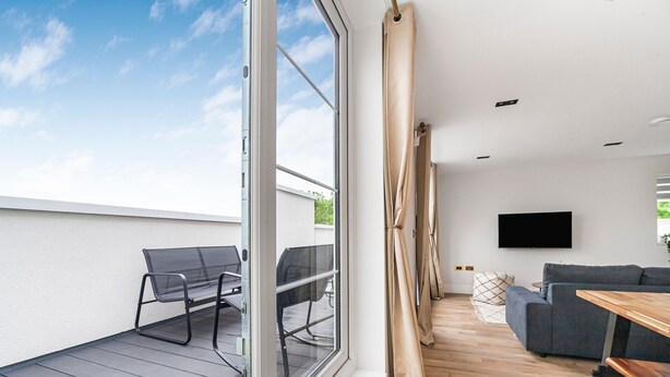 Una sala de estar moderna con un sofá, una mesa de madera y un televisor montado en la pared.