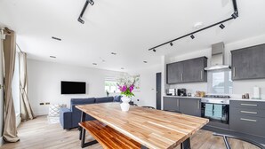 Una cocina moderna con armarios oscuros, una mesa de comedor de madera y un horno empotrado.