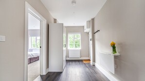 Un couloir doté d’un plancher en bois, de murs blancs et d’un radiateur blanc.