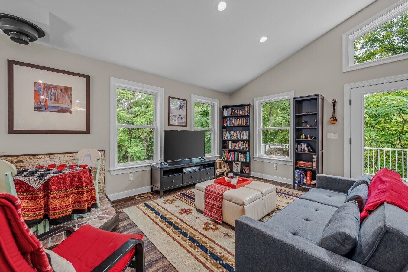 A spacious living room with a large window, a television, a bookshelf, and a sofa.