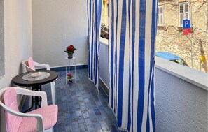 A balcony with striped curtains, a small table with a chair, and a potted plant. - Gorgeous apartment in Pula with WiFi (Pula)