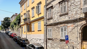 A street with parked cars and a building with a stone facade and yellow walls. - Gorgeous apartment in Pula with WiFi (Pula)