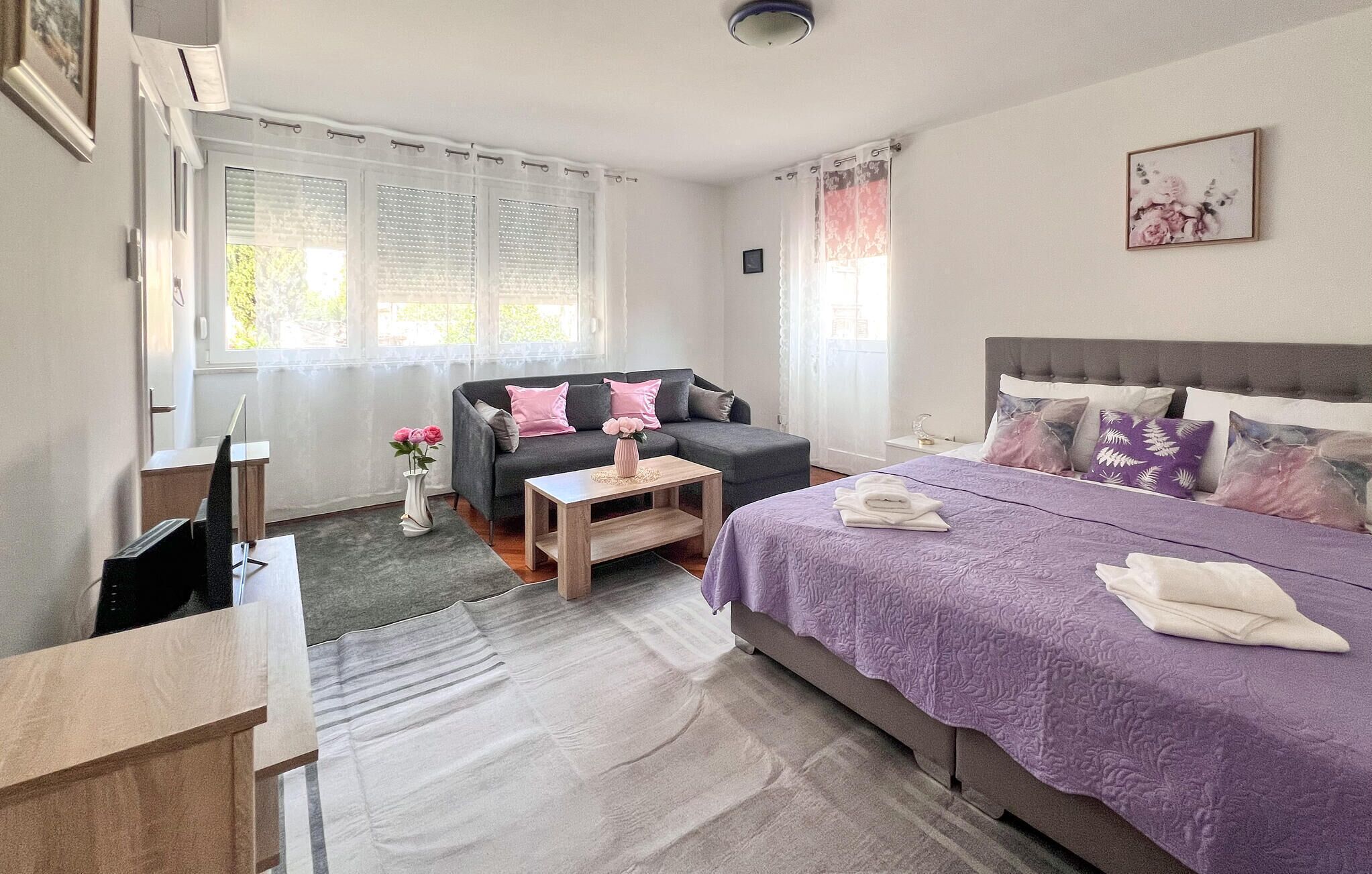 A bedroom with a bed, a sofa, a small table, and a desk.