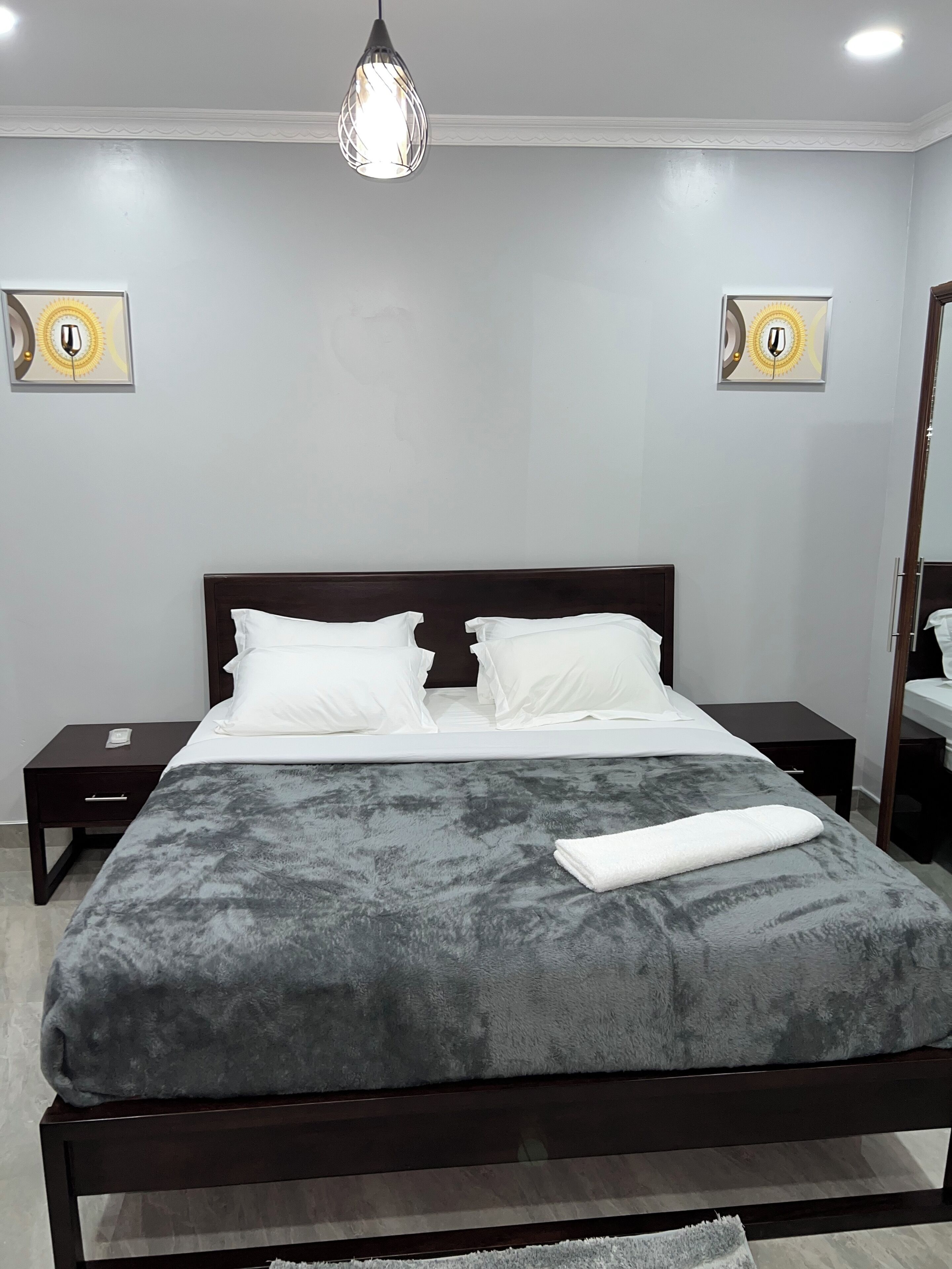 A neatly arranged bedroom with a large bed, two bedside tables, and a hanging light fixture.
