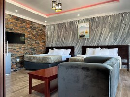 Habitación de hotel con dos camas, televisión, pared de mármol y un cuadro.
