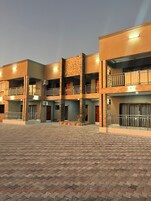 Un edificio de varios pisos con balcones, unidades de aire acondicionado y un patio empedrado.