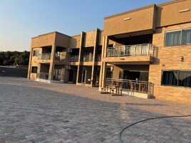 Un edificio de varios pisos con balcones, un patio empedrado y cielo despejado.