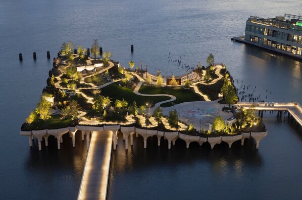 An aerial view of a waterfront property with a landscaped garden, a dock, and a building with multiple levels.