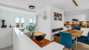 A modern kitchen with white cabinets, a wooden dining table, and blue chairs.