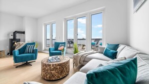 A modern living room with a fireplace, a sofa set, a coffee table, and large windows offering a view of the outdoors.
