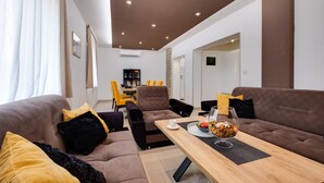 Una sala moderna con un conjunto de sofás, una mesa de comedor con sillas y una cocina al fondo.