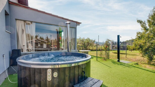 Un jacuzzi en un patio trasero con una casa al fondo.