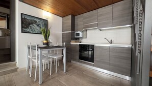 A modern kitchen with a dining area, featuring a wooden ceiling, grey cabinetry, a microwave, and a dishwasher. - Medieval IV - Historic Experience in Como (Como)