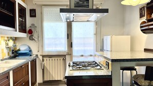 Una cucina con piano cottura a gas, una finestra e frigorifero.