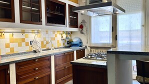 Una cucina con mobili in legno, un fornello a gas e una finestra con persiane.