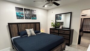 Un dormitorio con cama, cómoda, espejo y ventilador de techo.