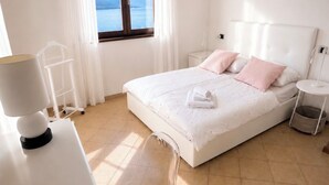 A bedroom with a bed, a desk, a chair, a nightstand, and a window with a view of the sea. - Cà Sulà, large detached house with garden and beautiful lake view (Maccagno con Pino e Veddasca)