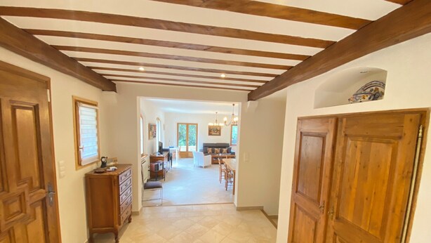 A spacious hallway with wooden beams, a dining area, and a kitchen in the background. - 06CB : Pretty country house for 8 (Tourrettes-sur-Loup)