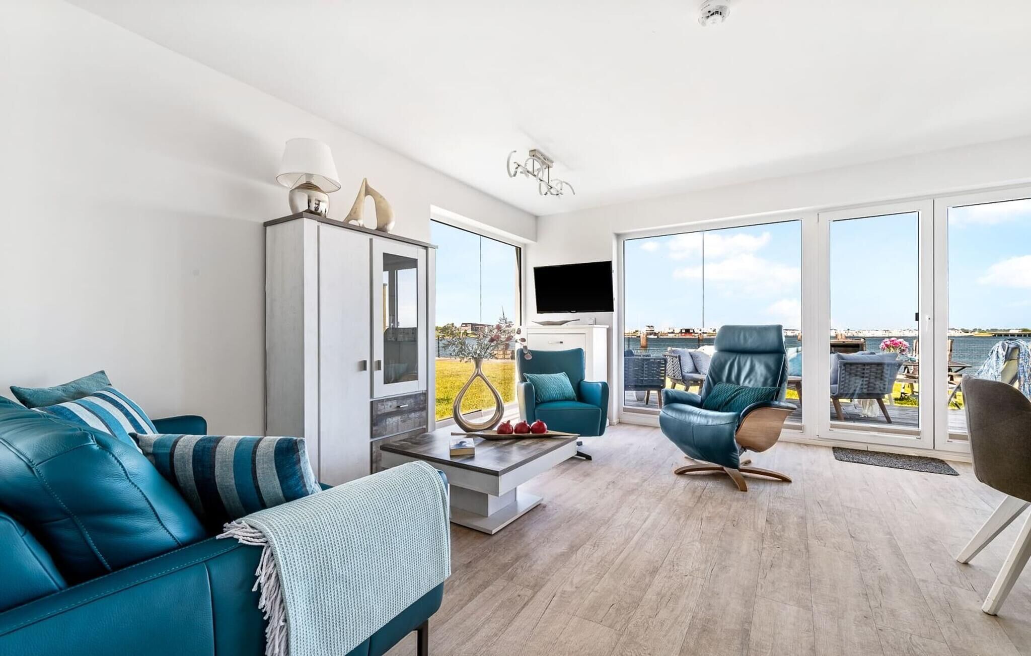 A modern living room with a sofa, a chair, a cabinet, and a TV.