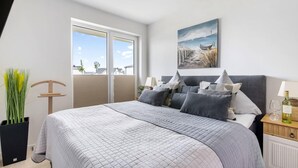 Une chambre avec un grand lit, une vue par la fenêtre et un tableau accroché au mur.