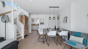 Een modern interieur met een eethoek, een bank en een trap.