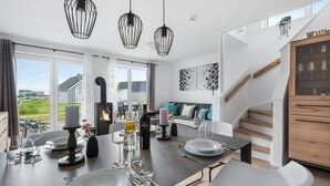 Een moderne keuken met een centraal eiland, een eethoek en een trap naar een slaapkamer op een entresol.