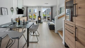 Een moderne keuken met een centraal eiland, een eetgedeelte met stoelen en uitzicht op het buiten.