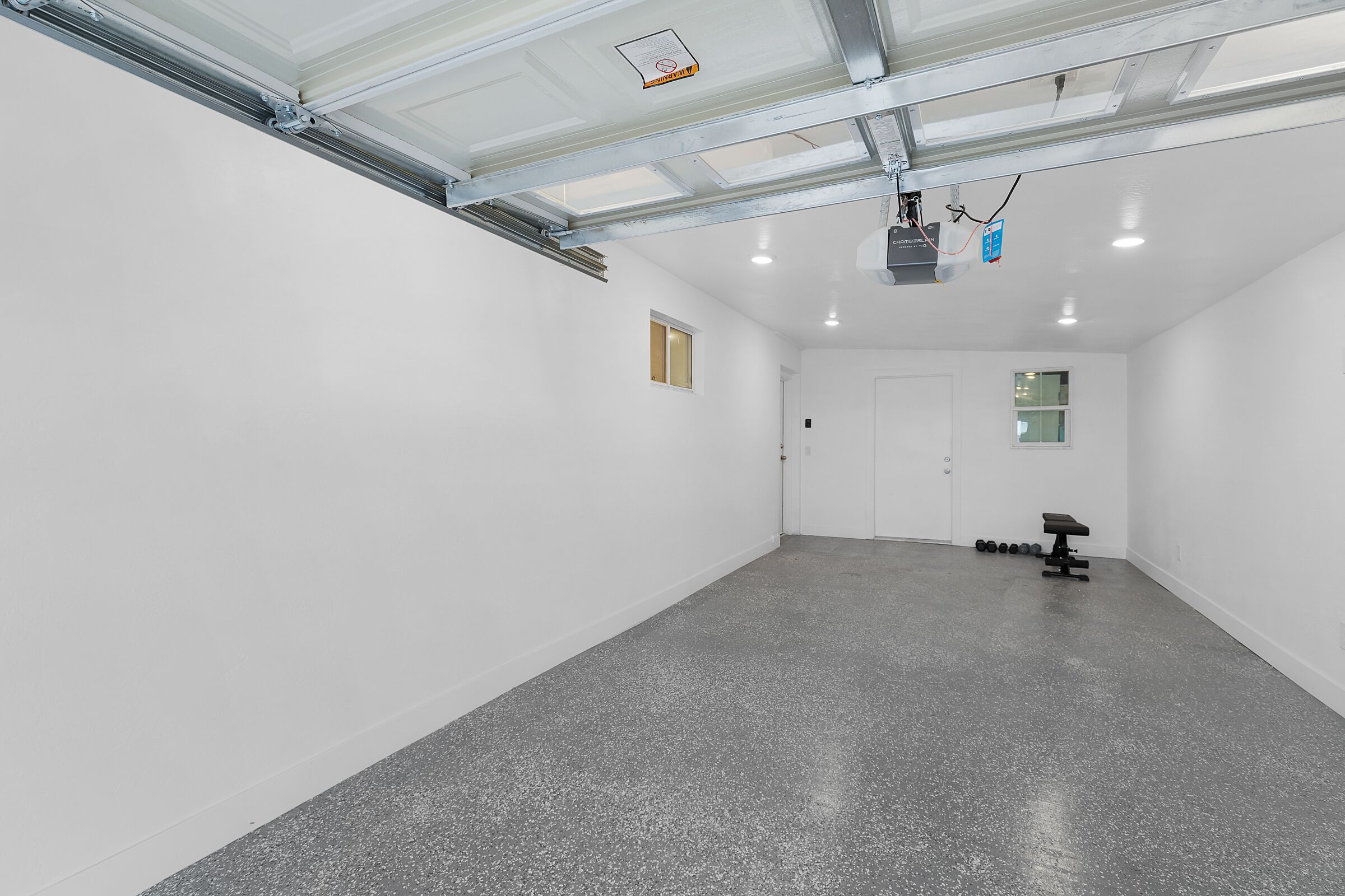 A spacious, well-lit room with a polished concrete floor, a bench, and a door leading to another area.
