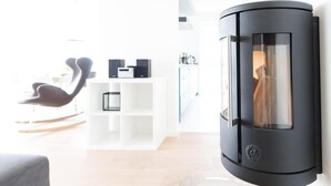 Un salón moderno con chimenea negra, estanterías blancas y un sofá gris.