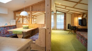 A cozy cabin interior with a wooden dining table, bench seating, a television, and a sofa. - Haus Katharina - Dorfblick (Kaprun)