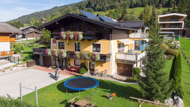 A two-story building with a balcony, a trampoline, and a small garden area. - Haus Katharina - Dorfblick (Kaprun)