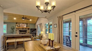 Una cocina acogedora con techo de madera, chimenea de piedra y comedor con mesa y banco de madera.