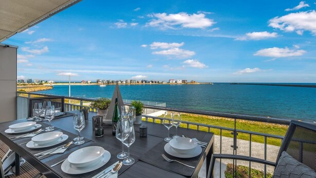 Mesa de jantar posta para seis com vista para o mar e uma vila costeira.