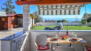 A dining area with a table set for two, overlooking a scenic view of the sea and mountains. - 1 bedroom lovely apartment in Ika (Ika)