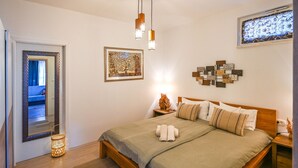 A bedroom with a wooden bed, a nightstand, a wall art piece, and a hanging light fixture. - 1 bedroom lovely apartment in Ika (Ika)