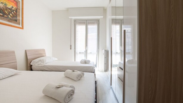 Habitación de hotel con dos camas, un espejo grande y vistas a la ciudad desde las ventanas.