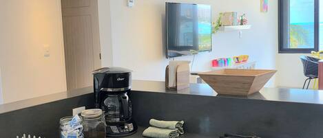 A modern kitchen with a gas stove, coffee maker, and a flat-screen TV.