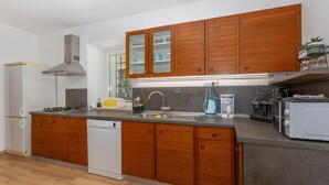 Eine moderne Küche mit Holzschränken, einem eingebauten Geschirrspüler, einem Herd, einer Kaffeemaschine und einem Toaster.