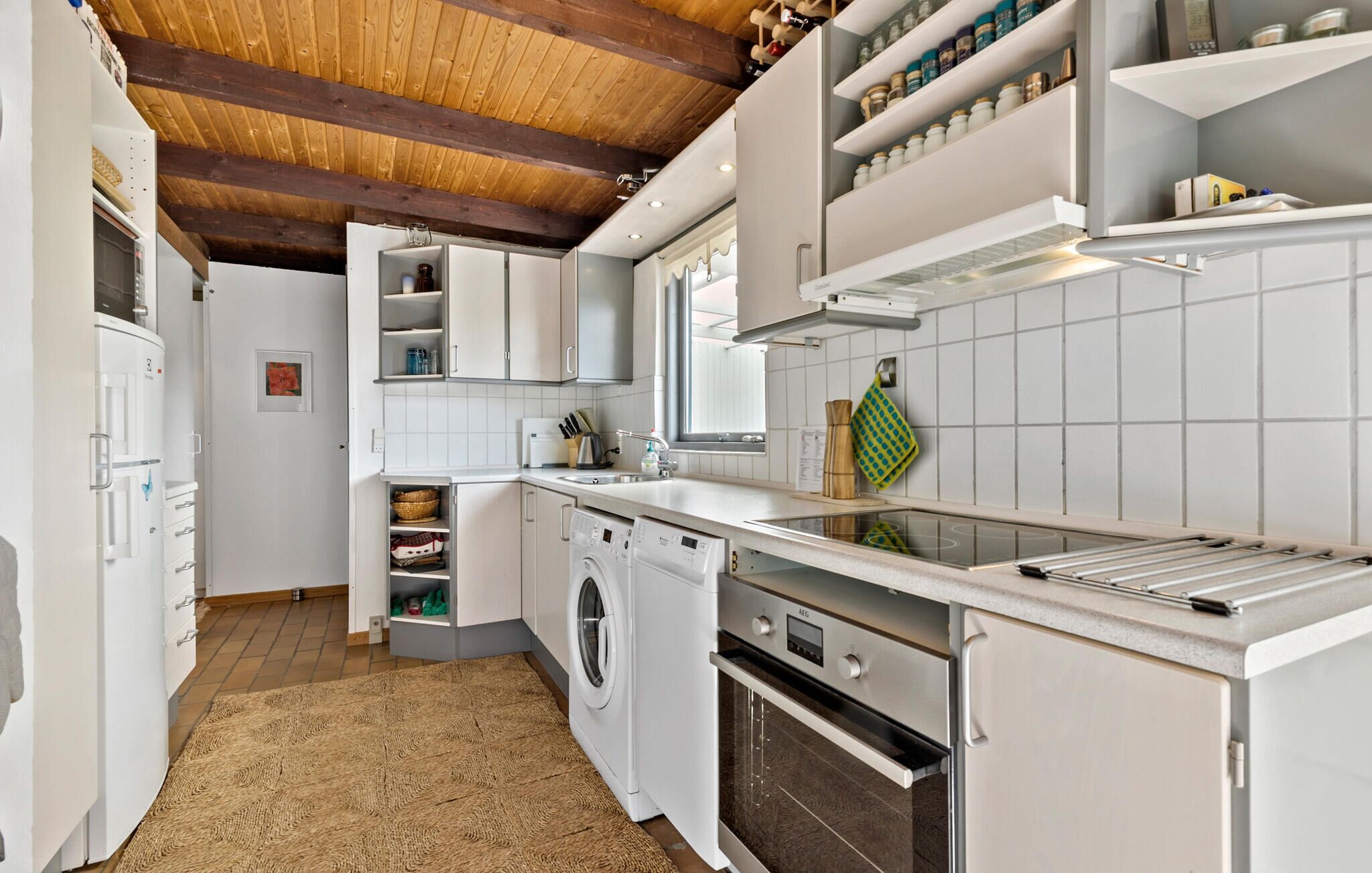 A modern kitchen with white cabinetry, a built-in oven, a dishwasher, and a stainless steel countertop.