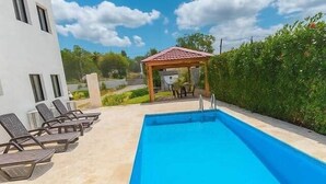 A swimming pool with lounge chairs and a gazebo. - Spacious Apartment w/ Secure Private Parking (Puerto Plata)