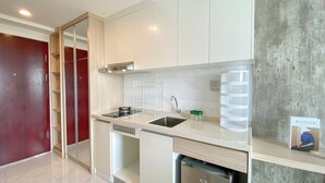 A modern kitchen with a sink, dishwasher, and a countertop with a water dispenser. - Warm And Homey Studio At Sky House Alam Sutera Apartment (Tangerang)