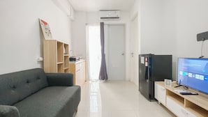 A modern living room with a grey sofa, a TV, a wooden cabinet, and a door leading to another room.