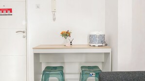 A small kitchenette with a white fridge, a coffee maker, and two green stools.