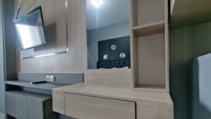 A modern kitchen with a built-in microwave, a countertop with a sink, and a cabinet with a mirror. - Cozy Living Studio The Alton Apartment (Semarang)