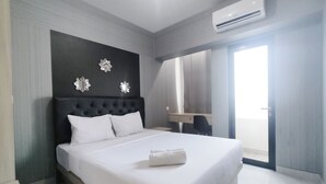 A modern hotel room with a large bed, a dark headboard, and a bathroom with a mirror and sink. - Cozy Living Studio The Alton Apartment (Semarang)