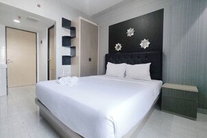 Habitación de hotel moderna con una cama grande, cabecera oscura y decoración en la pared.