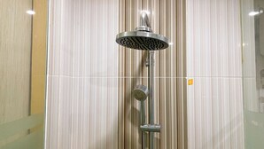 Una doccia con soffione a pioggia e doccetta, sullo sfondo una parete a righe.