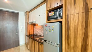 Una cucina compatta con mobili in legno, un forno a microonde integrato, un frigorifero e un piano cottura a gas.