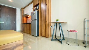 Una cucina compatta con mobili in legno, un frigorifero e un piccolo tavolo con una pianta.